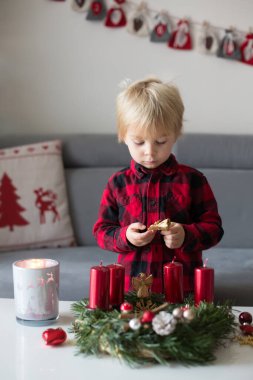 Küçük tatlı sarışın çocuk, evde çelenk yapıyor, dekore ediyor.