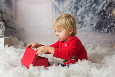 Tatlı sarışın çocuk, karla ve Noel dekorasyonuyla oynuyor, stüdyo fotoğrafı.