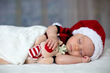 Tutmak oyuncak Santa şapka ve kot giyen küçük uyku yeni doğan oğlu,