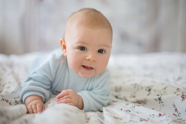 冬の朝の白い明るい寝室で愛らしい男の子 生まれたばかりの子供のベッドでリラックス 自宅の家族の朝 おなか時間笑って喜んで自宅中に新生児の子供 — ストック写真