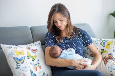 Genç anne yeni doğmuş bebeğini evde emziriyor.