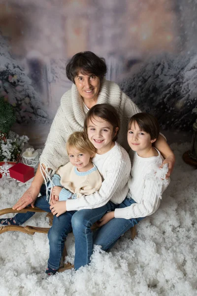 祖母と3人の孫 男の子 雪の中でクリスマスの肖像画を持って スタジオはそりで撮影 — ストック写真