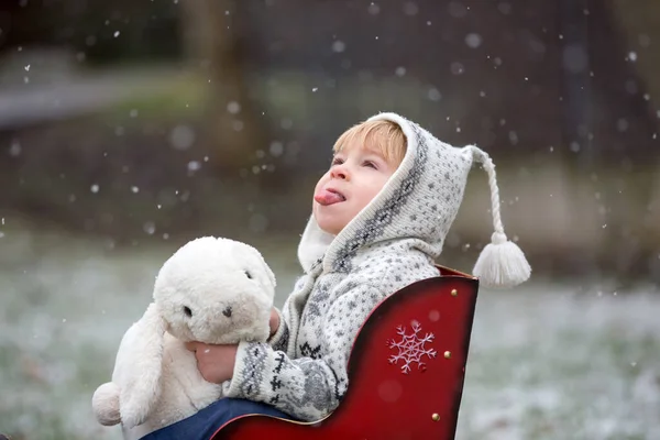 美しいブロンドの幼児の子供 男の子 手作りのニットセーター最初の雪と公園で遊んで 楽しんで — ストック写真