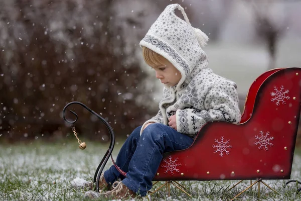 美しいブロンドの幼児の子供 男の子 手作りのニットセーター最初の雪と公園で遊んで 楽しんで — ストック写真