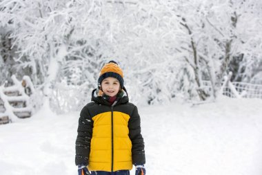 Tatlı mutlu çocuk, ormanın derinliklerinde karda oynuyor.