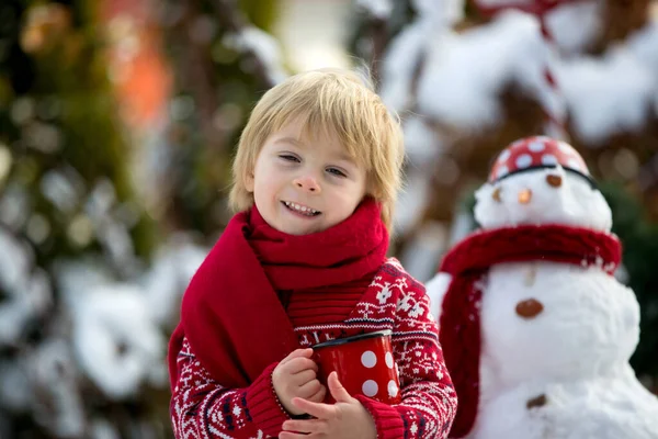 甘いブロンドの幼児の子供 男の子 雪と庭で遊ぶ 雪だるまを作る 幸せな子供の冬の時間屋外 — ストック写真
