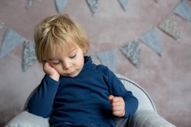 Şirin sarışın çocuk, çocuk, küçük bebek koltuğunda oturuyor, kitap okuyor, elinde çiçekler, stüdyo içi çekimler