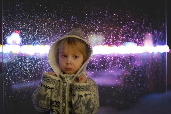 小さな子供 幼児の男の子 雪の中で屋外に落ちる窓の後ろに立って クリスマスの時間 — ストック写真