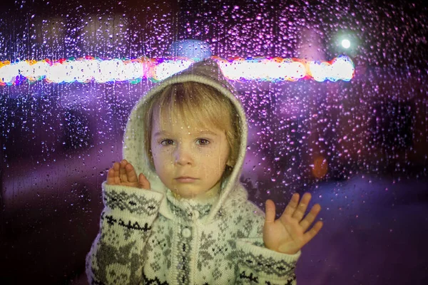 小さな子供 幼児の男の子 雪の中で屋外に落ちる窓の後ろに立って クリスマスの時間 — ストック写真