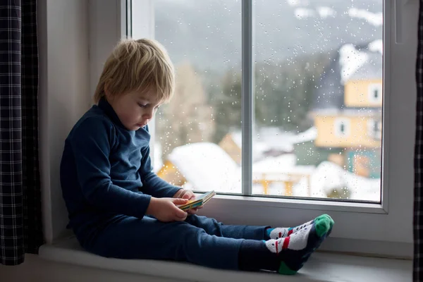 Kisgyerek Ablakon Nézi Havazást Kis Könyvet Olvas — Stock Fotó