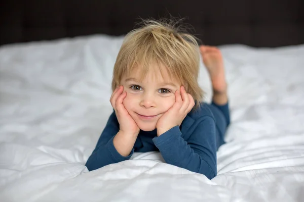 かわいい子がベッドに横になって小さなおもちゃで遊んで幸せそうに笑って — ストック写真