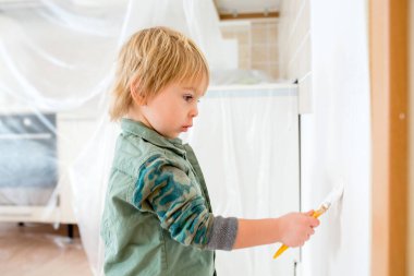 Şirin çocuk, babasıyla yeni evde duvar boyuyor.