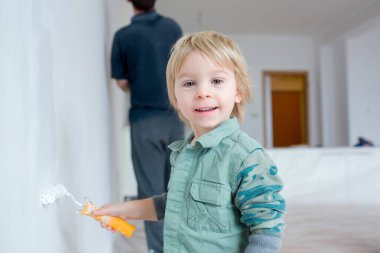 Şirin çocuk, babasıyla yeni evde duvar boyuyor.
