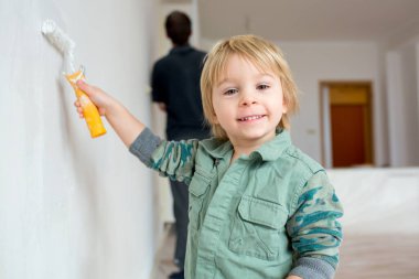 Şirin çocuk, babasıyla yeni evde duvar boyuyor.