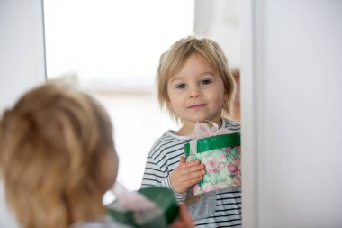 Küçük tatlı sarışın çocuk, küçük oğlan, kucağında anneler günü için küçük bir hediye var.