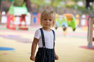 Tatlı çocuk, oğlum, yaz vakti oyun bahçesinde oynuyor.