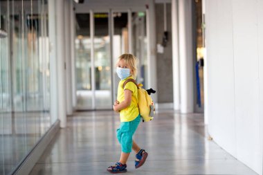 Küçük çocuk, yüz maskesi takan çocuk ve havaalanında dezenfekte kullanıyor, bir uçuş için hazırlanıyor, tüm önlemlerle aile gezisi.