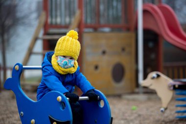 Küçük çocuk, çocuk, Covid salgını sırasında yürürken tıbbi maske takıyor.