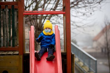 Küçük çocuk, çocuk, Covid salgını sırasında yürürken tıbbi maske takıyor.