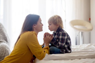 Anne ve bebek el ele tutuşuyorlar, yatağa uzanıyorlar, mutlu aile zamanları.