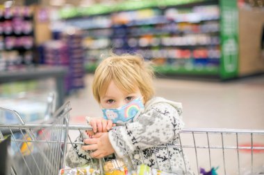 Covid salgını sırasında süpermarkette tıbbi maske takan tatlı bir çocuk.