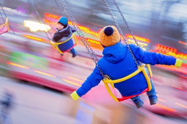 Çocuk, sevimli çocuk gün batımında salıncakta sallanıyor, hareket bulanıklığı, renkli bir arka plan.