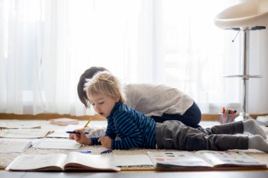 Çocuk, evde yerde okul ödevi yaparken Quartene 'de, çocuk evde eğitim görüyor.