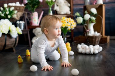 Küçük tatlı sarışın çocuk, stüdyoda paskalya süslemesi olan çocuk, yerde sürünüyor.