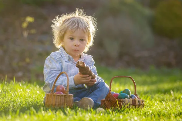 Μικρό Αγοράκι Τρώει Σοκολατένιο Λαγουδάκι Στον Κήπο Ηλιοβασίλεμα Αυγά Πασχαλιάς — Φωτογραφία Αρχείου