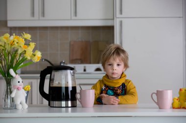 Yorgun anne, sabahları kahve koymaya çalışıyor. Uykusuz bir geceden sonra mutfak masasında uzanmış kahve içmeye çalışan bir kadın.