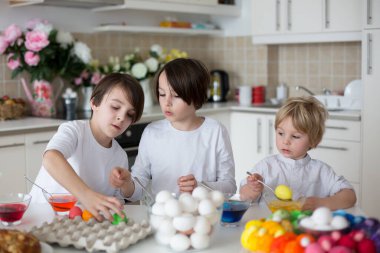 Çocuklar, erkek kardeşler, evde paskalya için yumurta boyama.