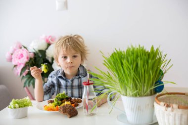 Küçük çocuk, sarışın çocuk, haşlanmış sebze, brokoli, patates ve havuç yiyen evde kızarmış tavuk eti, taze pişirilmiş sağlıklı yiyecekler.