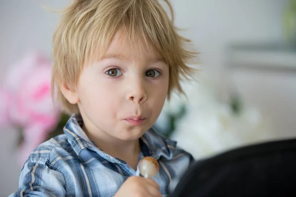 Niño Pequeño Niño Rubio Lamiendo Piruleta Casa Mientras Película Tableta — Foto de Stock