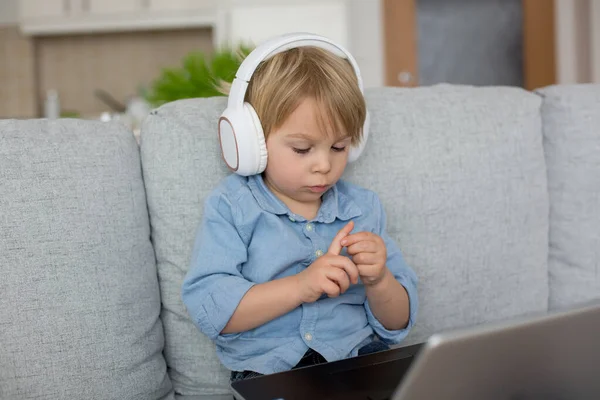 可爱的金发碧眼的孩子 穿着休闲装的男孩 在家操劳计算 带着耳机和电话 — 图库照片
