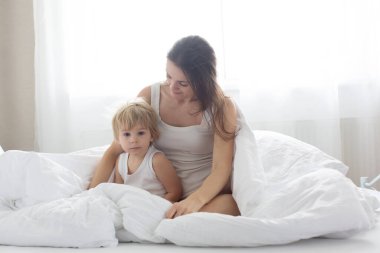 Güzel sarışın çocuk ve annesi, sabahları evde oynuyorlar, gülüyorlar, gülüyorlar ve birlikte eğleniyorlar.