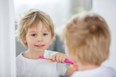Tatlı çocuk, sarışın çocuk, evde dişlerini fırçalıyor, izole edilmiş.