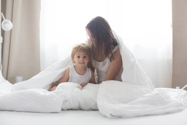 아름다운 금발의아이와 어머니 침대에서 아침에 집에서 즐거운 시간을 — 스톡 사진