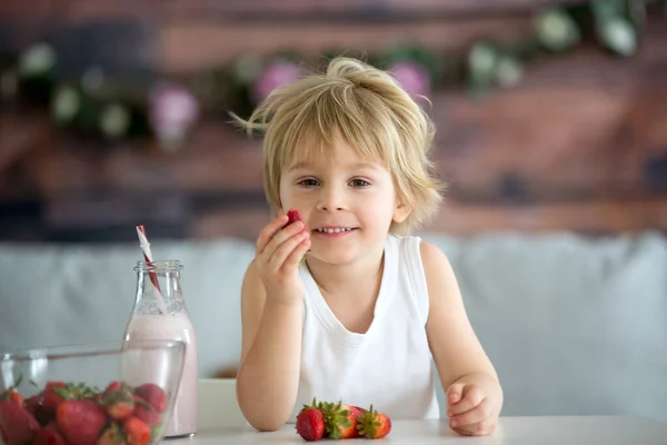 かわいい幼児の子供 ブロンドの男の子 スムージーを飲んで 家でイチゴを食べる — ストック写真