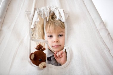 Sarışın çocuk, evde doldurulmuş maymunla çadırı kaplıyor.