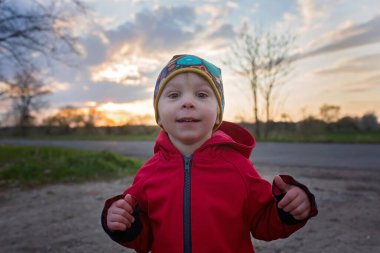 Tatlı çocuk, parkta köpekli çocuk, gün batımında tarlada koşuyor.
