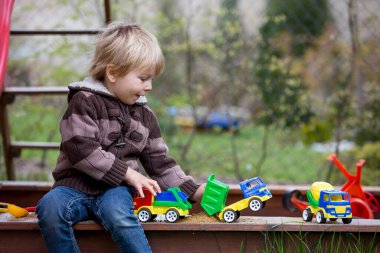 Küçük çocuk, çocuk, bahçede kum havuzunda oynuyor.