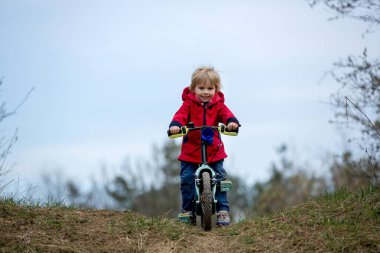 Küçük çocuk, baharda parkta bisiklet sürmeyi öğreniyor.