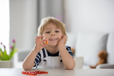 Tatlı küçük çocuk, küçük çocuk, alfa omega 3 çocuk ilavesi yiyor evde daha iyi bağışıklık kazanmak için vitamin hapları alıyor.