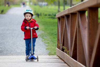 Çocuk, çocuk, parkta scooter süren, bahar güneşli bir gün.