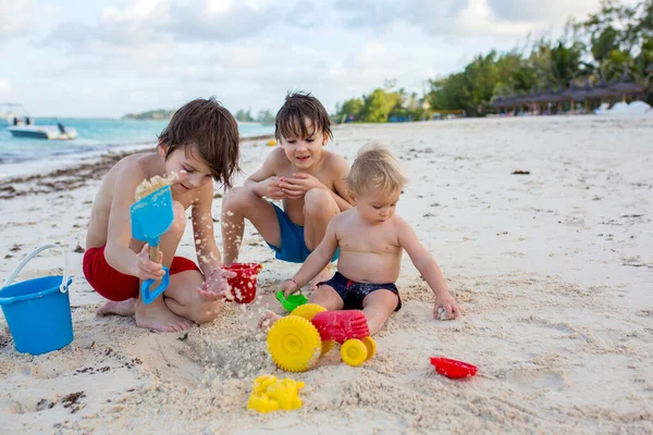 热带海滩上与玩海滩玩具的兄弟姐妹们玩耍的可爱幼儿 — 图库照片