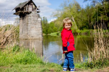 Çocuk, tuğla sütun üzerindeki eski ahşap kulübenin önünde duruyor, Çek Cumhuriyeti Avrupa 'sında Chotesov yakınlarında Radbuza Nehri' nde küçük bir kulübe.