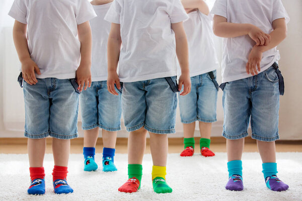 Children feet with different socks standing in rows, kids wearing different colorful socks