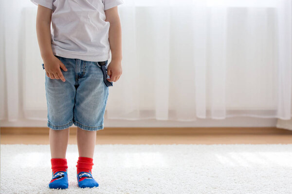 Child feet with different socks standing in rows, kids wearing different colorful socks