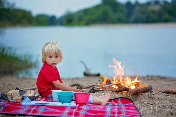 夏の川の近くの夜にピクニックやキャンプファイヤーをしている家族 — ストック写真