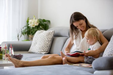 Sevimli anne, küçük bebeğiyle evde bulmaca yapıyor, kiraz yiyor.